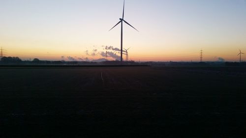 Electricity pylons on field at sunset