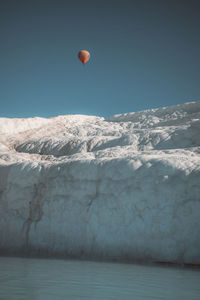 Hot air balloon flying over snowcapped mountain against sky