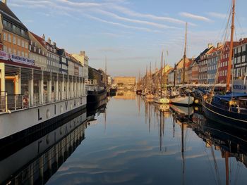 Sailboats moored on canal by buildings against sky