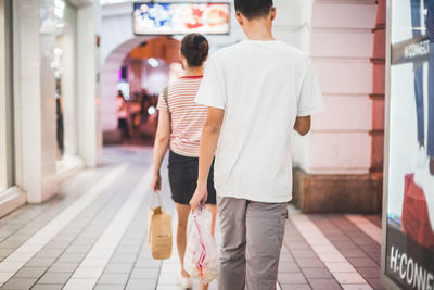 Rear view of men walking on road in city