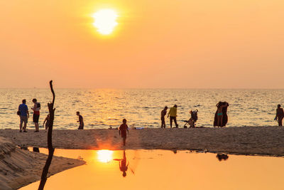 Group of people on beach during sunset