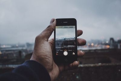 Cropped image of man photographing through smart phone