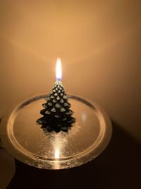 Close-up of illuminated candle on container