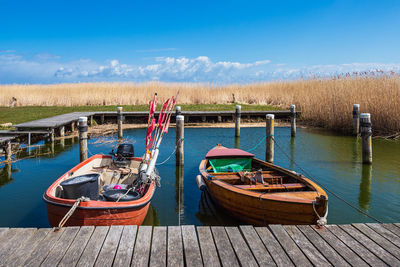 Fishing boats moored at lake against sky