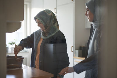 Women in headscarves cooking together for eid al-fitr at home