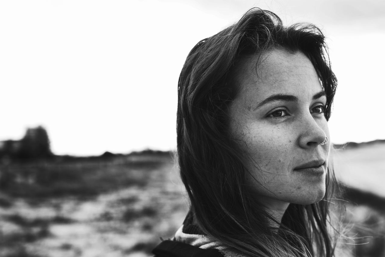 headshot, portrait, one person, focus on foreground, young adult, sky, real people, close-up, hair, looking away, lifestyles, young women, leisure activity, day, hairstyle, long hair, looking, nature, contemplation, outdoors, beautiful woman, human face