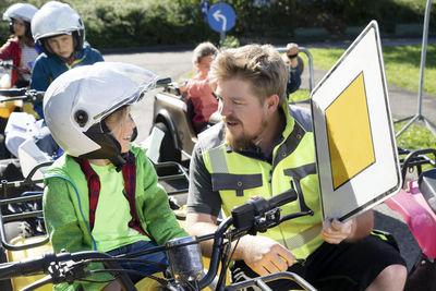 Trainer ecplaining traffic sign to boy sitting in quadbike