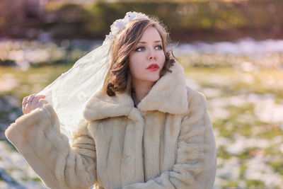 Portrait of young woman standing against trees