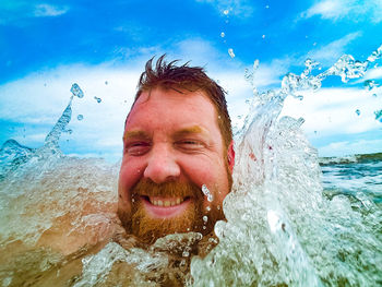 Close-up portrait of happy man swimming in sea against sky