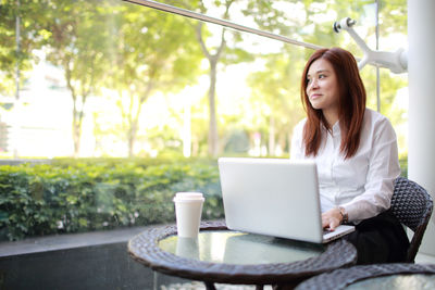 Smiling young woman using laptop while sitting in cafe