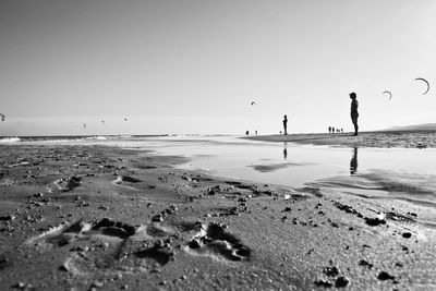 People standing on sand against sea at beach