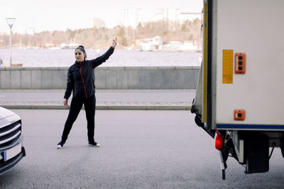 Young delivery woman guiding truck for parking on street