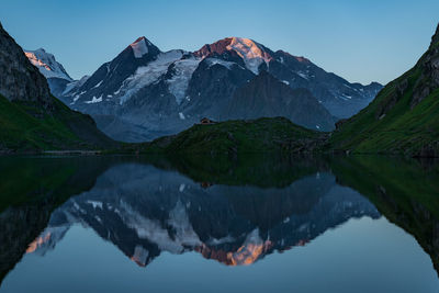 Scenic view of lake and mountains against clear blue sky