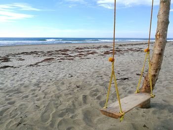 Deck chairs on beach against sky