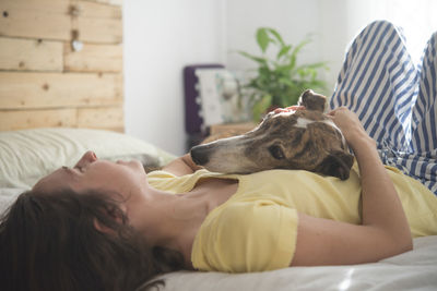 Woman with dog lying down on bed at home