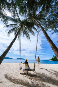 Men sitting on beach against sky