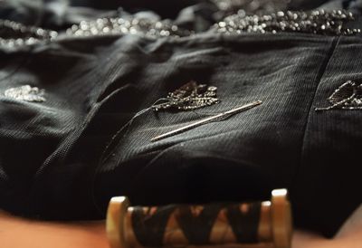 Black dress with needle spool on table at home