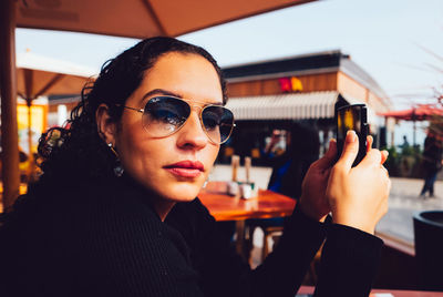 Portrait of young woman texting at an outdoor restaurant