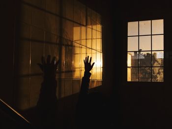 Silhouette people standing by window in dark room