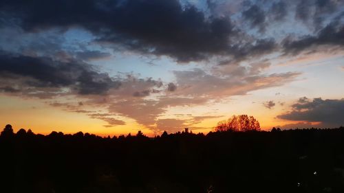 Silhouette landscape against dramatic sky during sunset