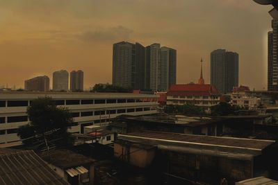 Modern buildings in city against sky during sunset