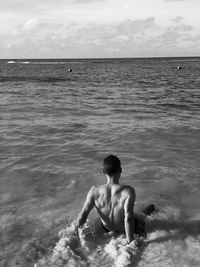 Full length of shirtless man at beach against sky