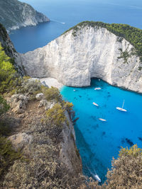 High angle view of cliff by sea against clear sky