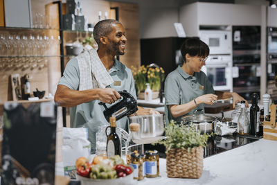 Multiracial male and female colleagues using modern kitchen appliances at store