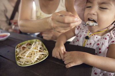 Mother feeding daughter with asian food