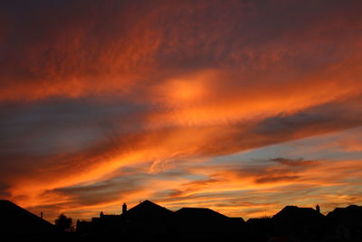 Silhouette buildings against orange sky