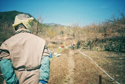 Rear view of farmer standing on agricultural field