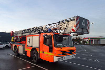 Front view of an orange fire truck standing in a large parking lot.