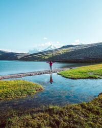 Woman standing by lake against sky