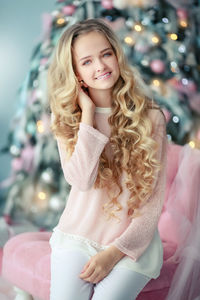 Portrait of smiling young woman standing against christmas tree