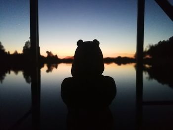 Silhouette of man by lake against sky during sunset