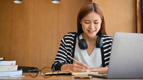 Smiling woman taking down notes at office