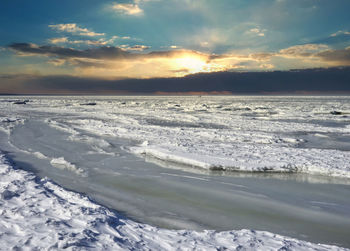 Scenic view of frozen lake against sky during sunset