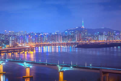 Illuminated bridge over river against sky at night