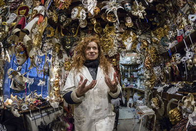 Low angle view of woman smiling while standing amidst masks in store