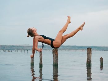 Young woman jumping on sea against sky