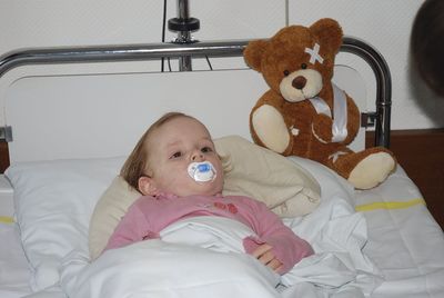 Girl with teddy bear on bed at hospital