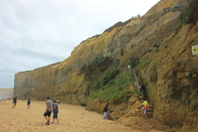 Low angle view of people walking on mountain against sky