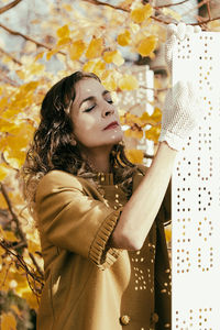 Woman with eyes closed standing against tree