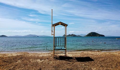 Lifeguard hut on beach against blue sky