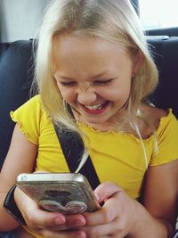 Close-up of girl holding mobile phone at home