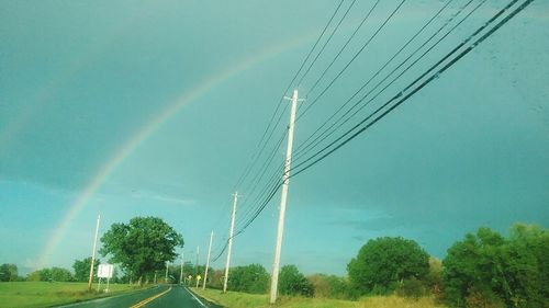View of rainbow over road against blue sky