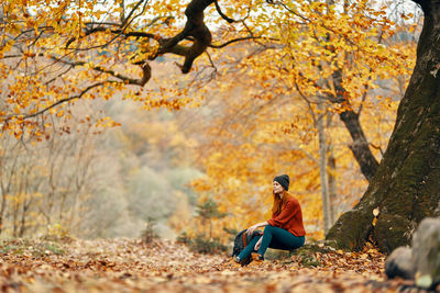 Full length of man sitting on street during autumn