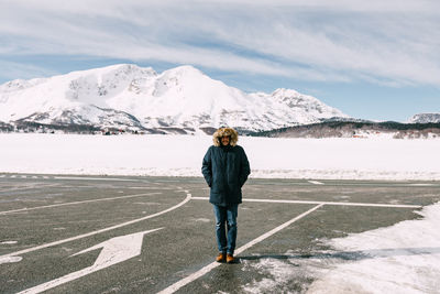 Rear view of man standing on snowcapped mountain against sky