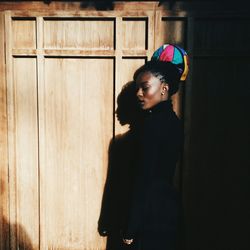 Young woman standing against wooden wall at home