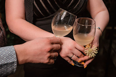 The clink of the glasses with light liquid in hands of a women and a man
